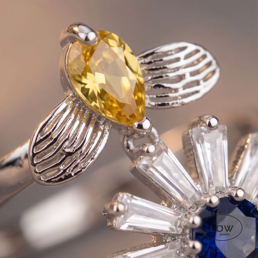 Sølvfarget justerbar fidget ring i kobber med roterende blomst og bie. Velg blå eller rosa blomsterkjerne. Fra LØW Jewelry.