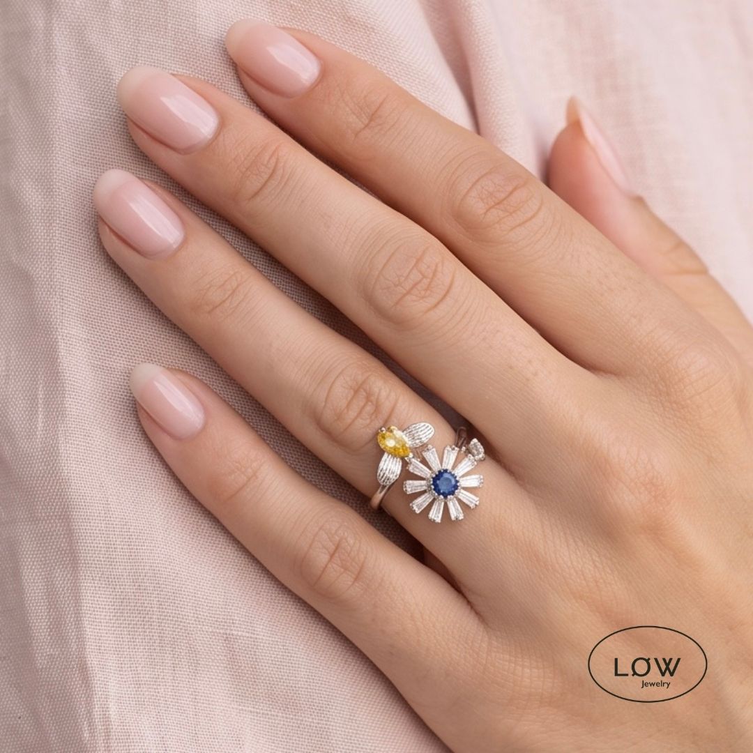 Sølvfarget justerbar fidget ring i kobber med roterende blomst og bie. Velg blå eller rosa blomsterkjerne. Fra LØW Jewelry.