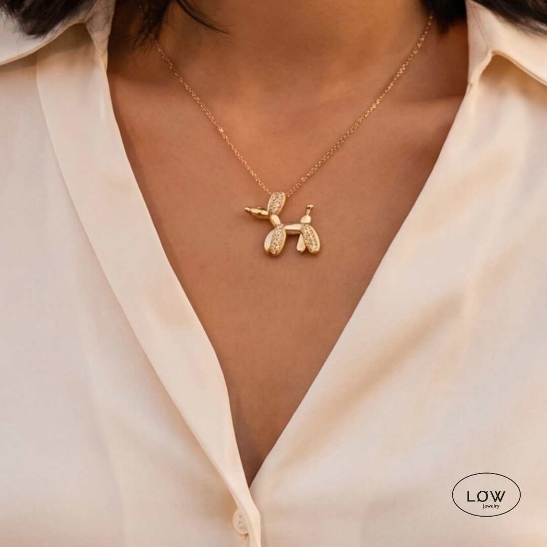 Lumi Balloon Dog Necklace Gold fra LØW Jewelry er et gullfarget halskjede med ballonghund og glitrende zircon. 40 + 5 cm.