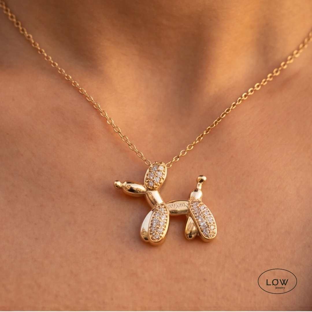 Lumi Balloon Dog Necklace Gold fra LØW Jewelry er et gullfarget halskjede med ballonghund og glitrende zircon. 40 + 5 cm.