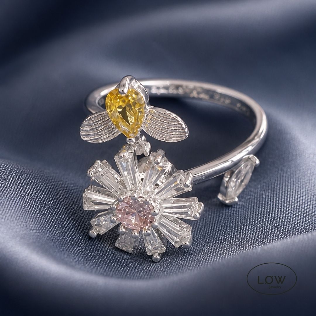 Sølvfarget justerbar fidget ring i kobber med roterende blomst og bie. Velg blå eller rosa blomsterkjerne. Fra LØW Jewelry.